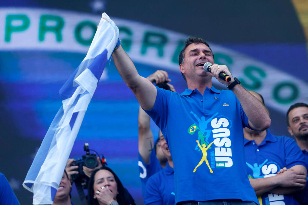 Flávio Bolsonaro waves an Israeli flag at a rally last July (Photo: Miguel SCHINCARIOL / AFP) ברזיל סנאטור פלביו בולסונרו פלאביו בולסונרו בנו של ז'איר בולסונרו עם דגל ישראל ב עצרת יוני 2026 צעדה למען ישו