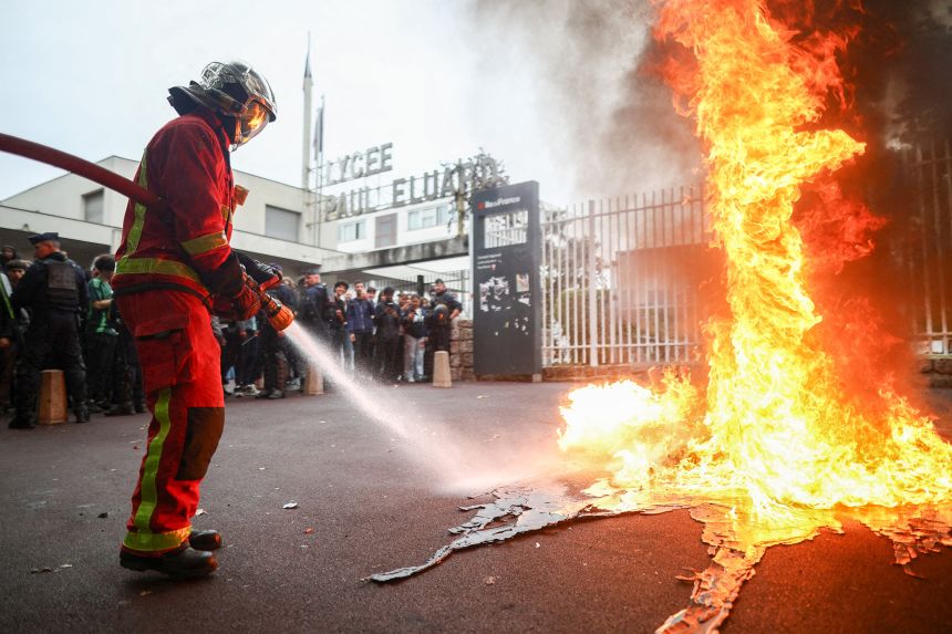 Firefighters extinguish fires as students gather in front of Paul Éluard secondary school in Saint-Denis, Paris, on Wednesday.