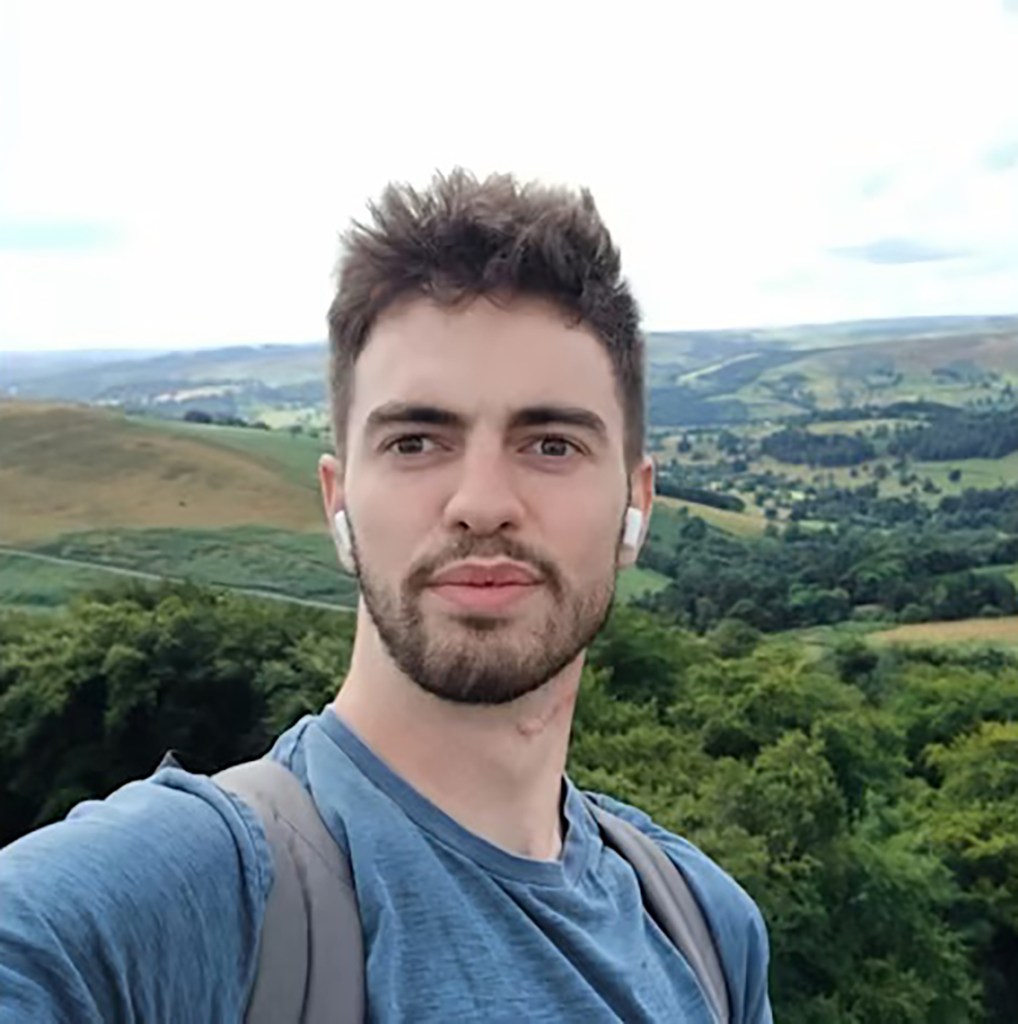 William Chapman takes a selfie outdoors in a scenic landscape.
