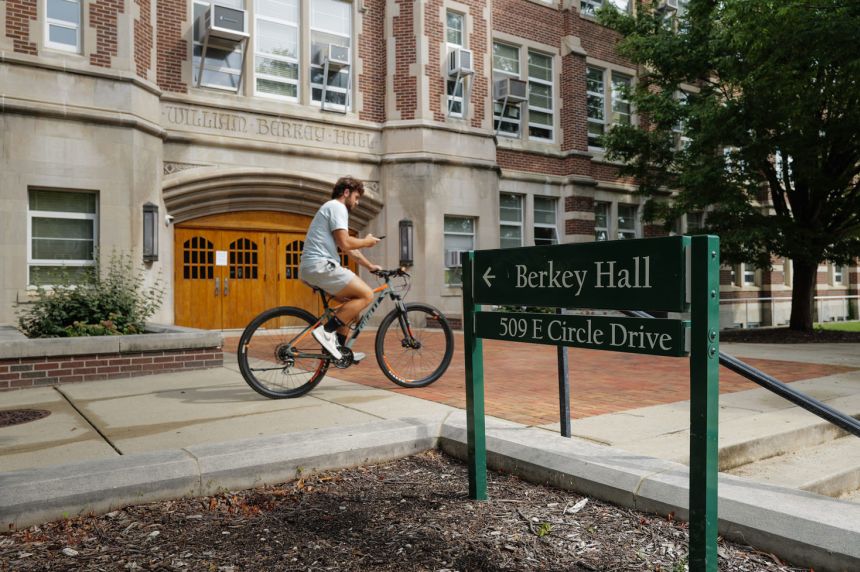 A man rides past Berkey Hall on the campus of Michigan State University on September 3.